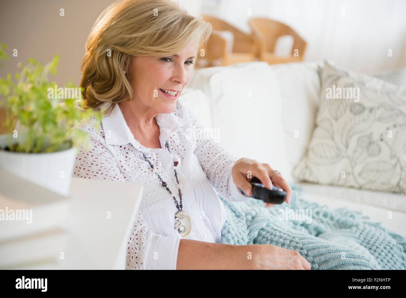 Caucasian woman watching television on sofa Stock Photo