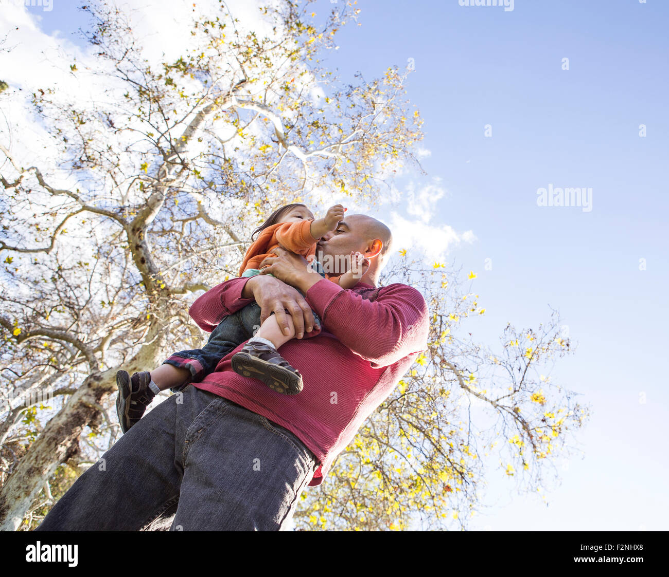 Low angle view of Hispanic father kissing son outdoors Stock Photo
