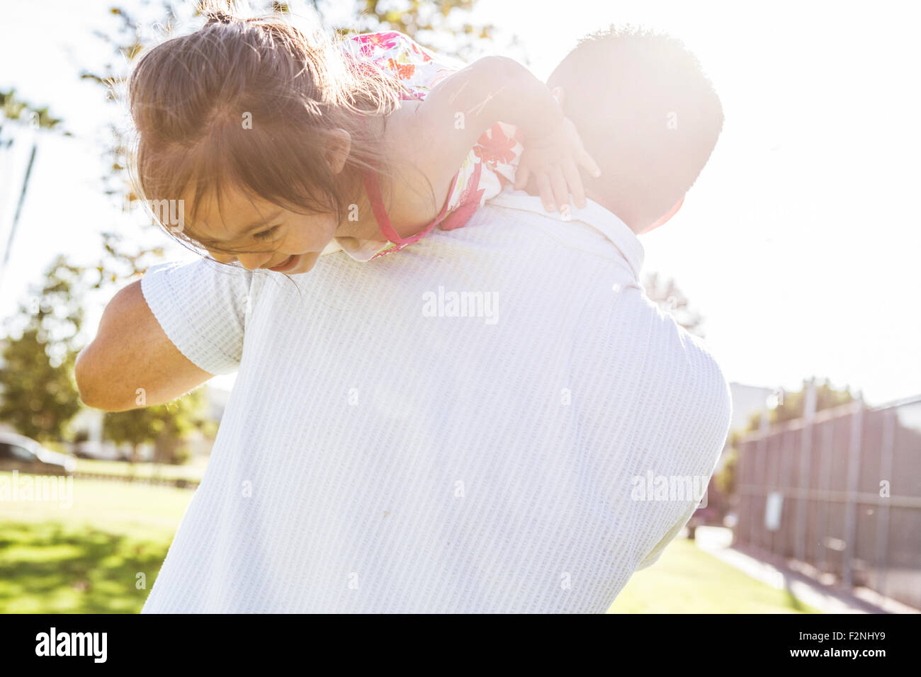 Hispanic father carrying daughter on shoulders Stock Photo