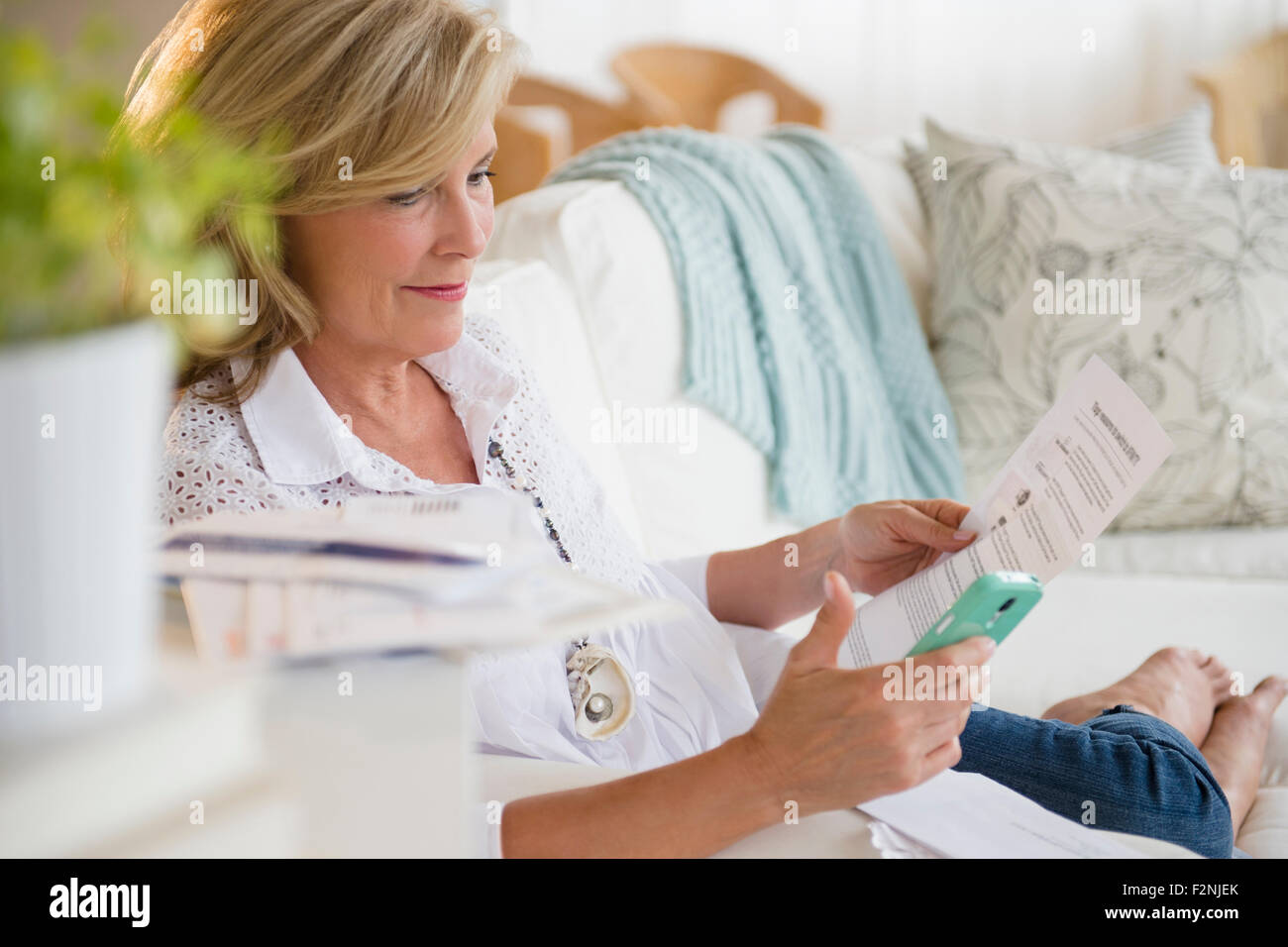 Caucasian woman paying bills online on cell phone Stock Photo