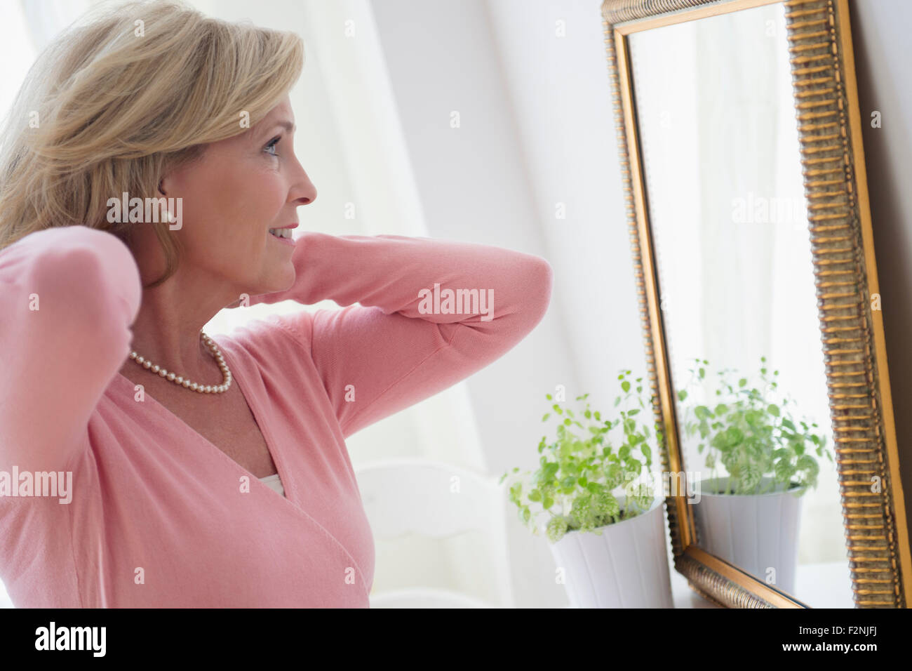 Caucasian woman admiring herself in mirror Stock Photo