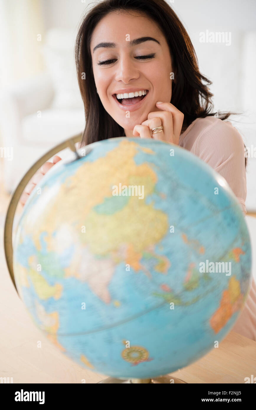 Woman admiring globe on desk Stock Photo