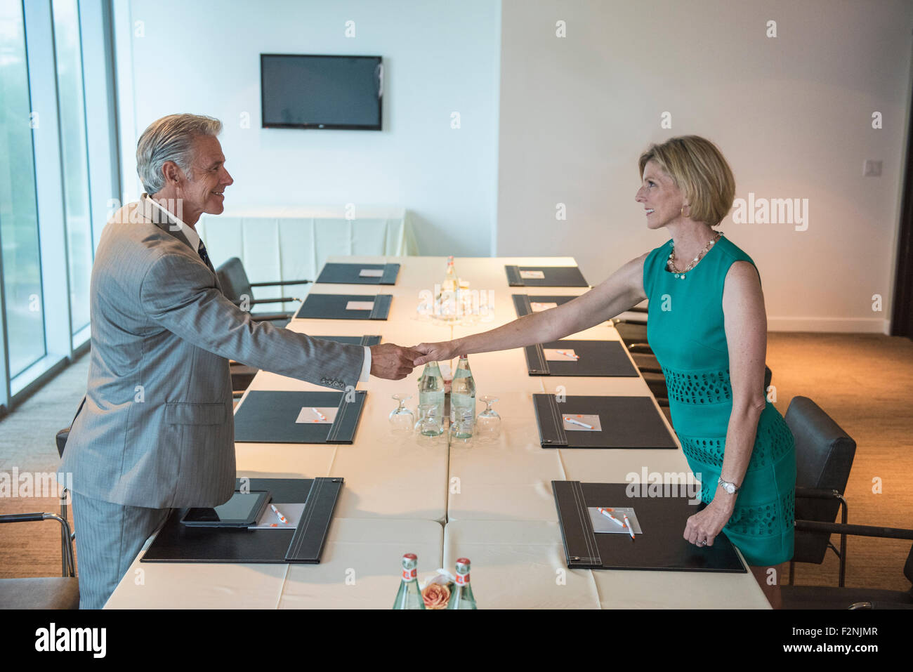 Caucasian business people shaking hands in conference room Stock Photo