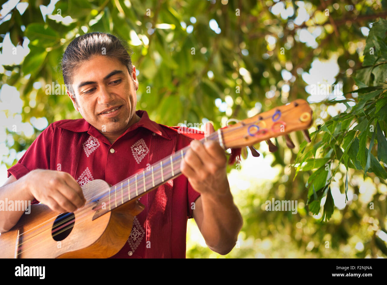 Hispanic musician performing in park Stock Photo