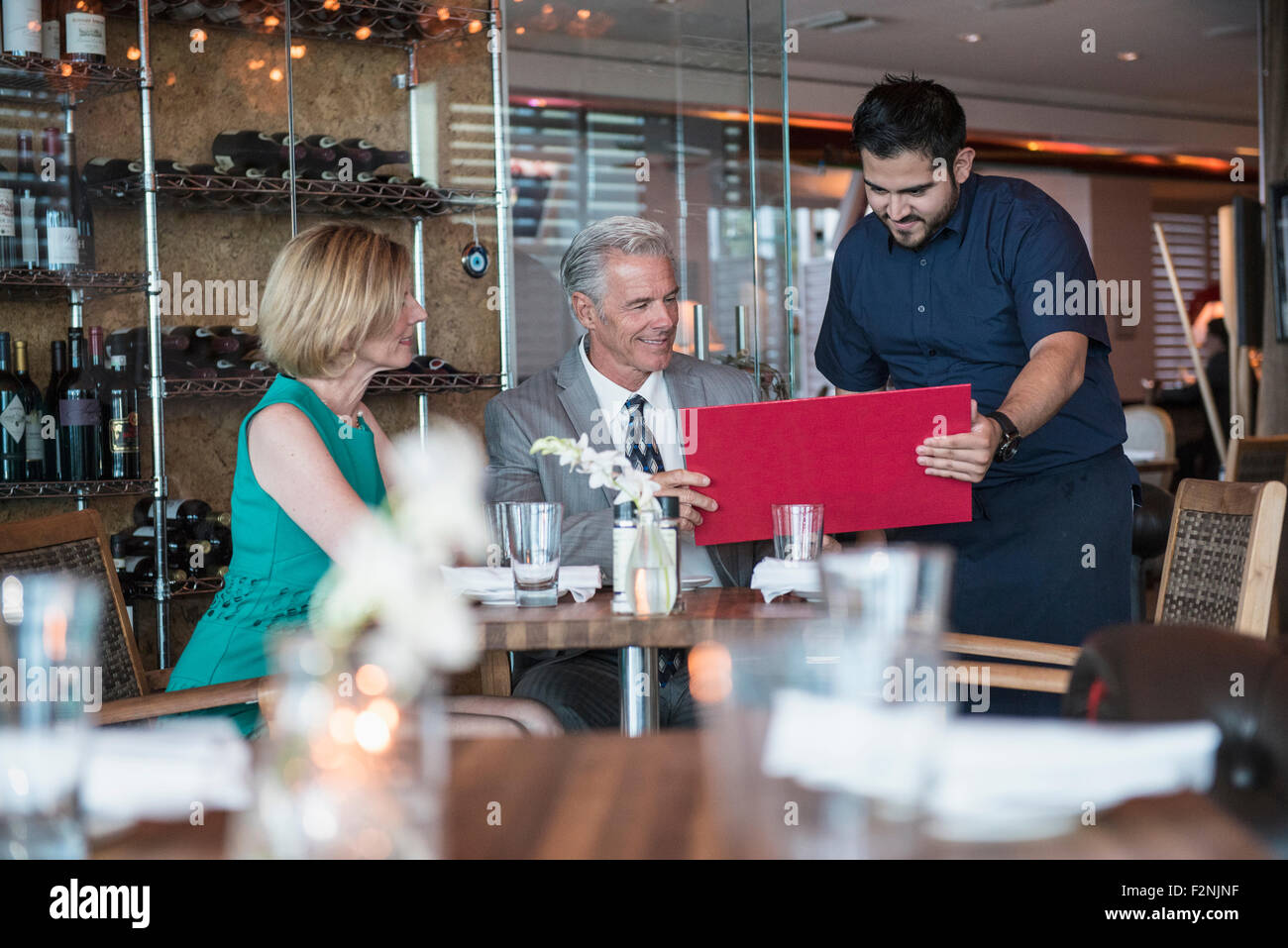 Waiter assisting couple with menu in restaurant Stock Photo