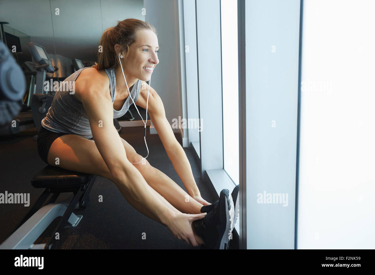 Smiling woman stretching in gym Stock Photo