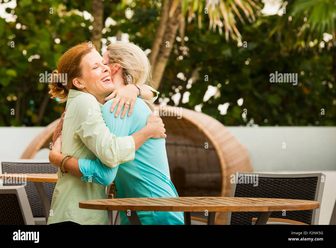 Caucasian women hugging on restaurant patio Stock Photo