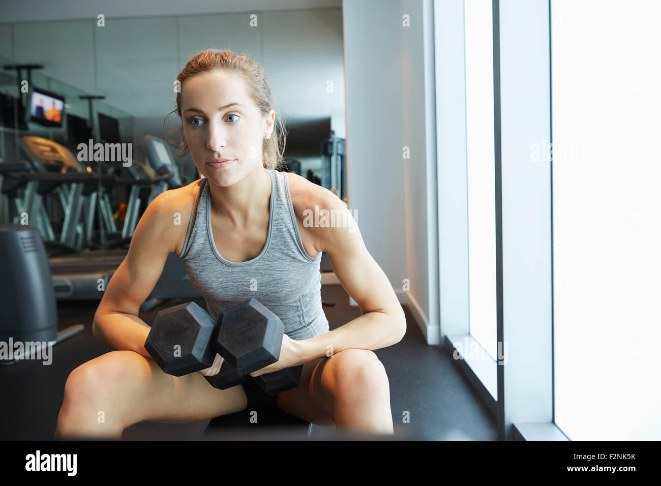 Serious woman lifting weights in gym Stock Photo