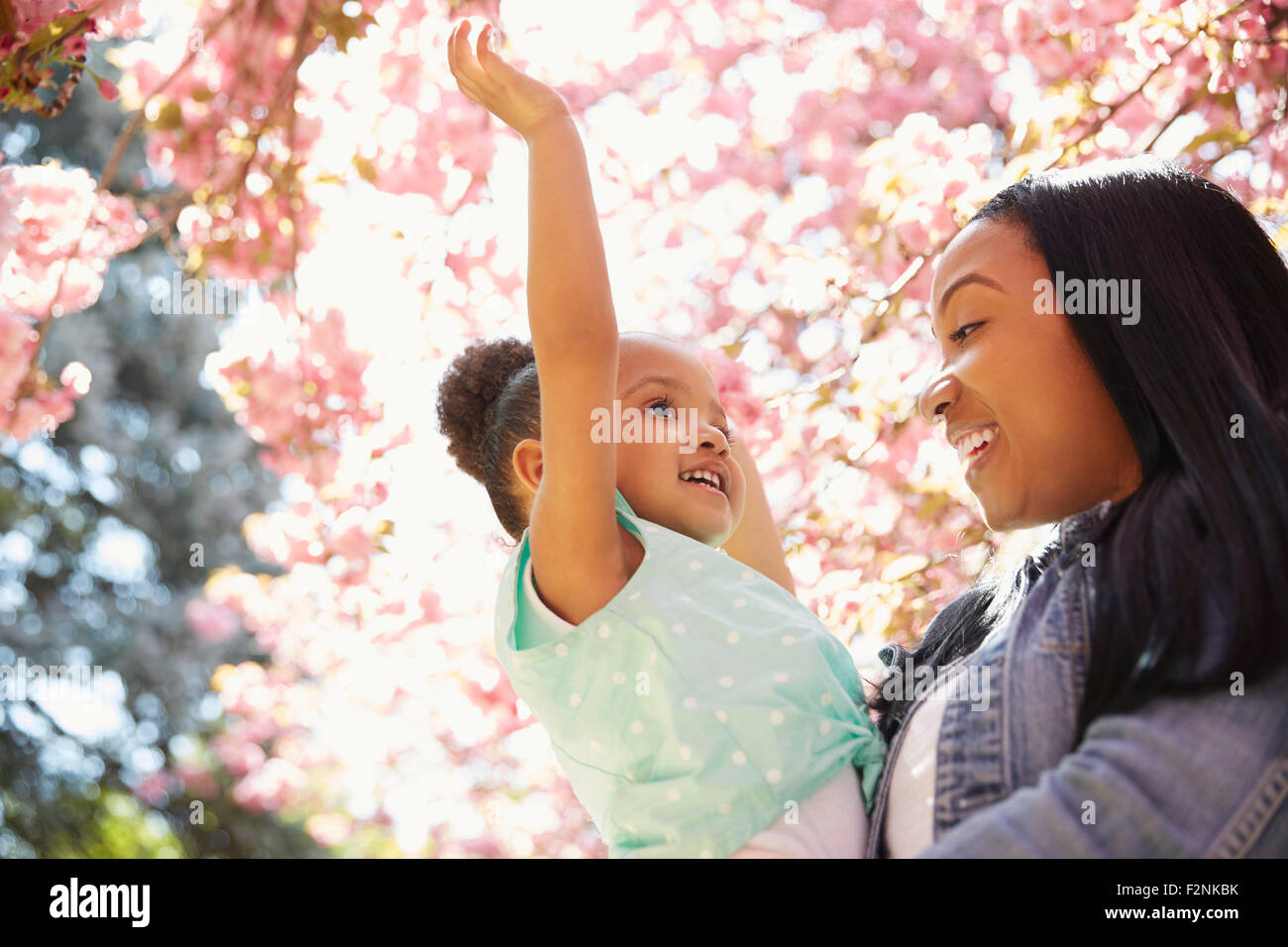 Mother and daughter under flowering tree in park Stock Photo