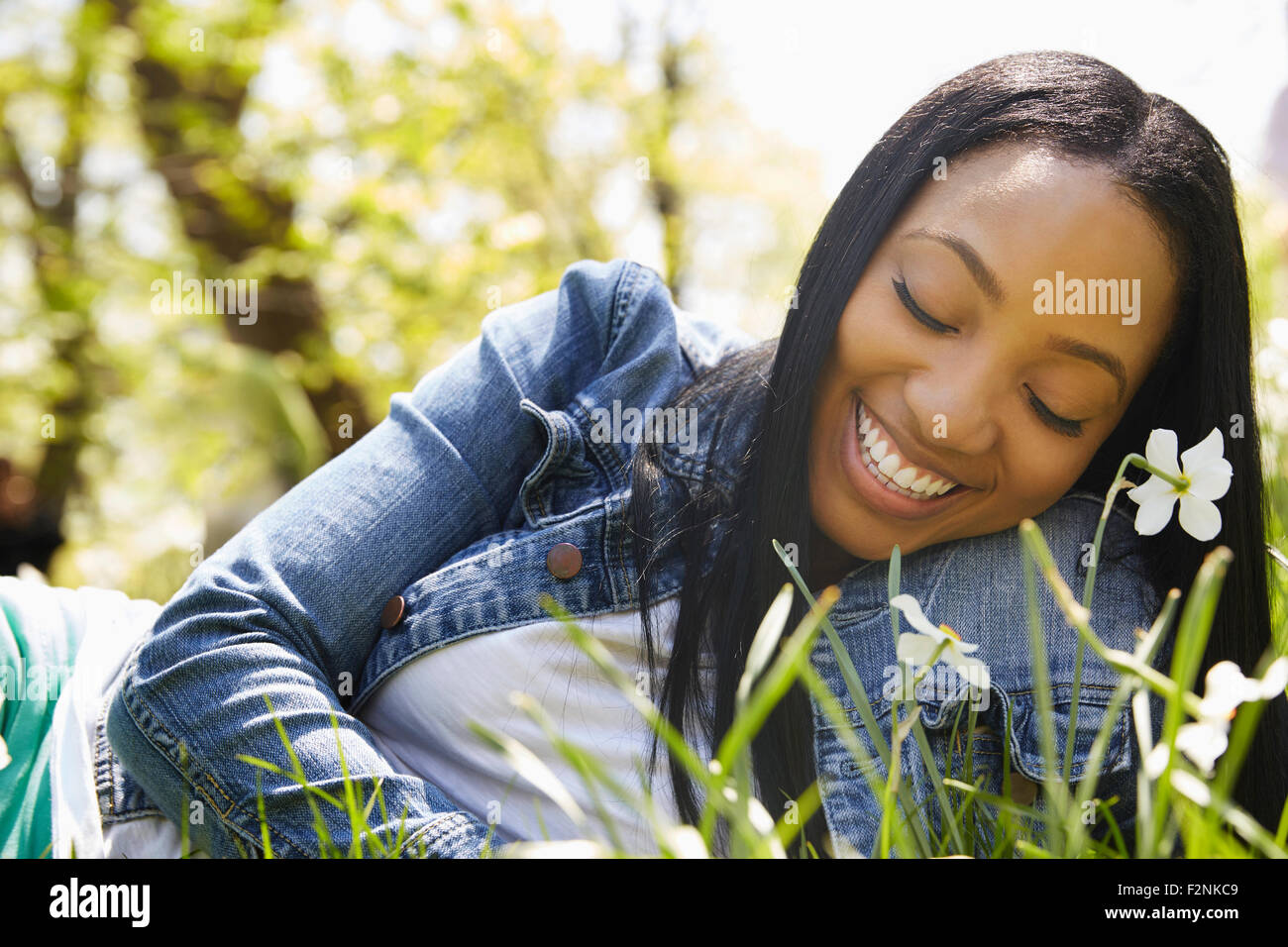 Black woman smiling in grass in park Stock Photo
