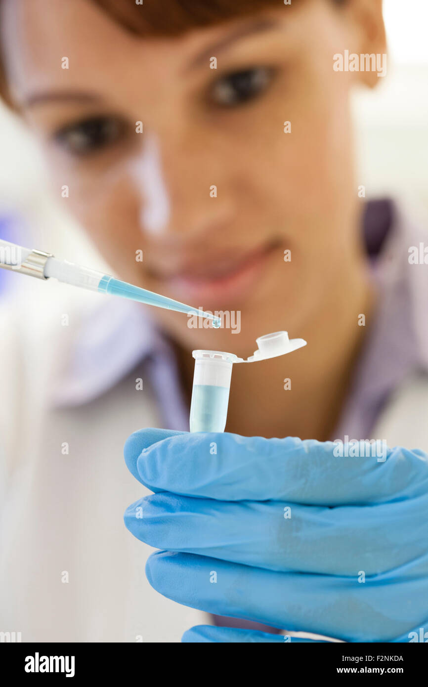 Mixed race scientist pipetting sample into test tube in laboratory Stock Photo