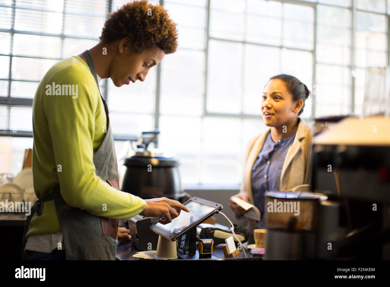 Mixed race barista assisting customer in coffee shop Stock Photo