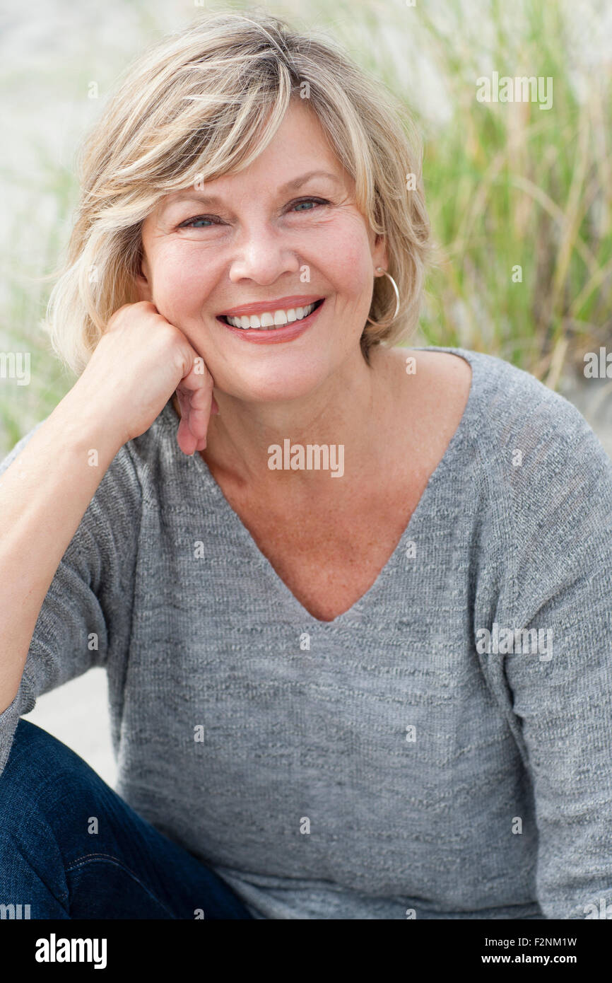 Smiling Caucasian woman sitting on beach Stock Photo
