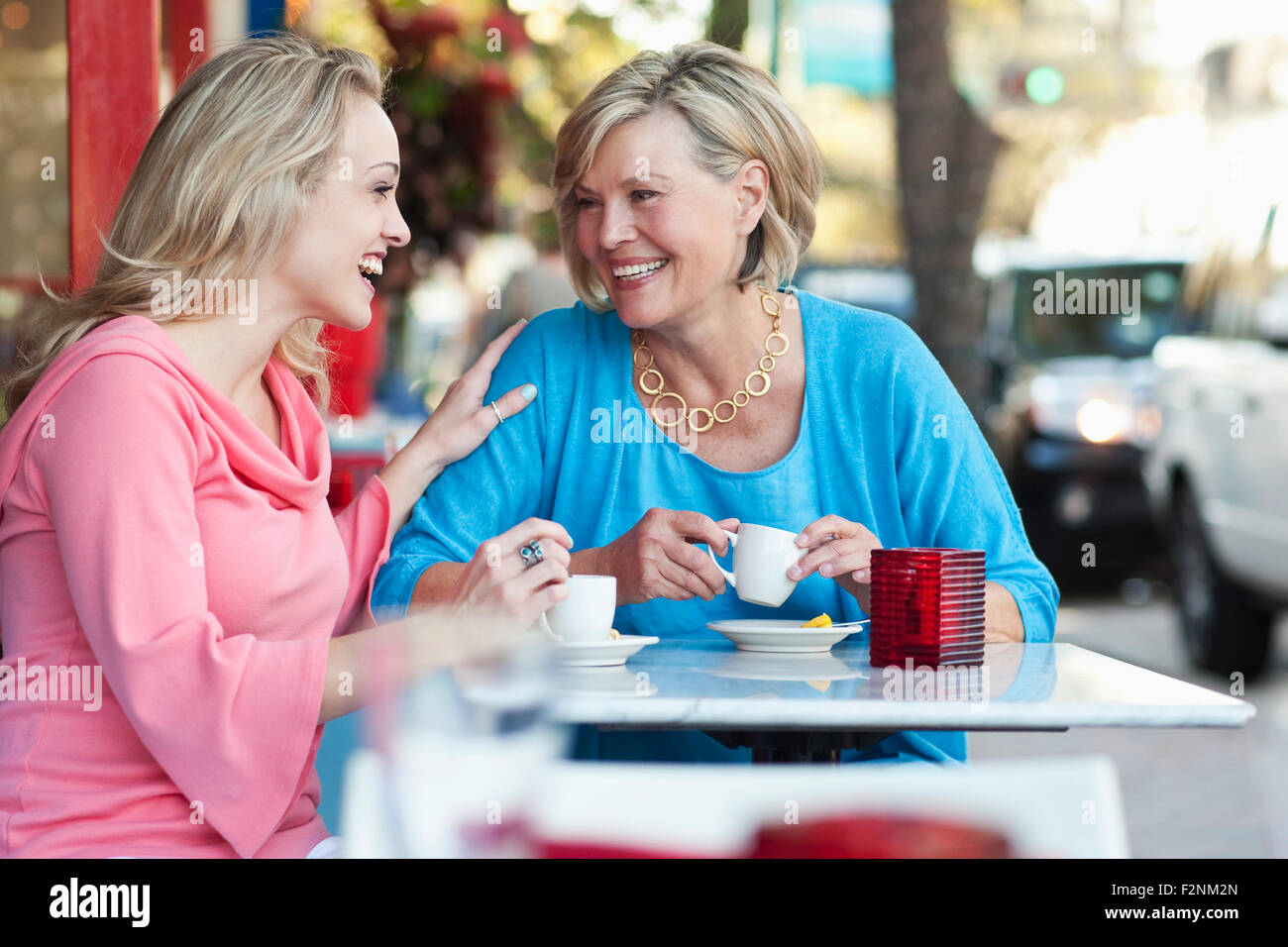 Caucasian mother and daughter drinking coffee at sidewalk cafe Stock Photo