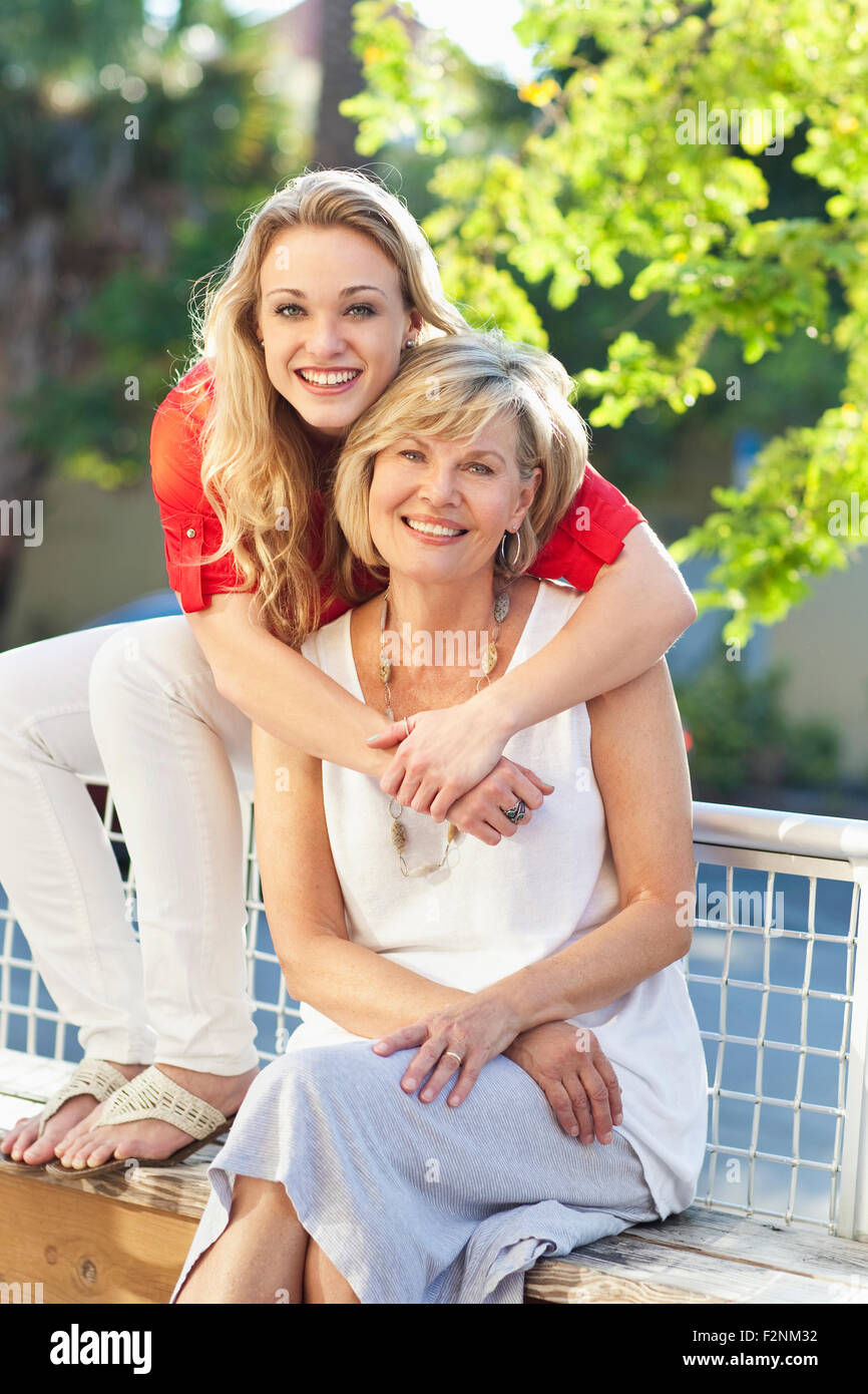 Caucasian mother and daughter hugging on bench Stock Photo