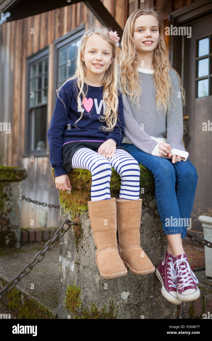Sisters sitting on mossy pedestal Stock Photo