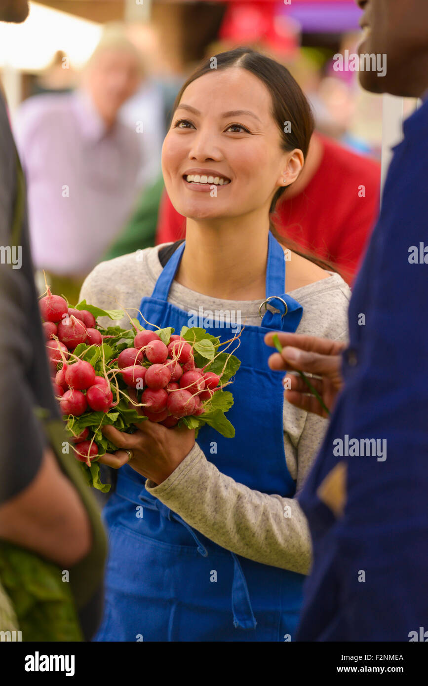 Clerk holding produce at farmers market Stock Photo Alamy