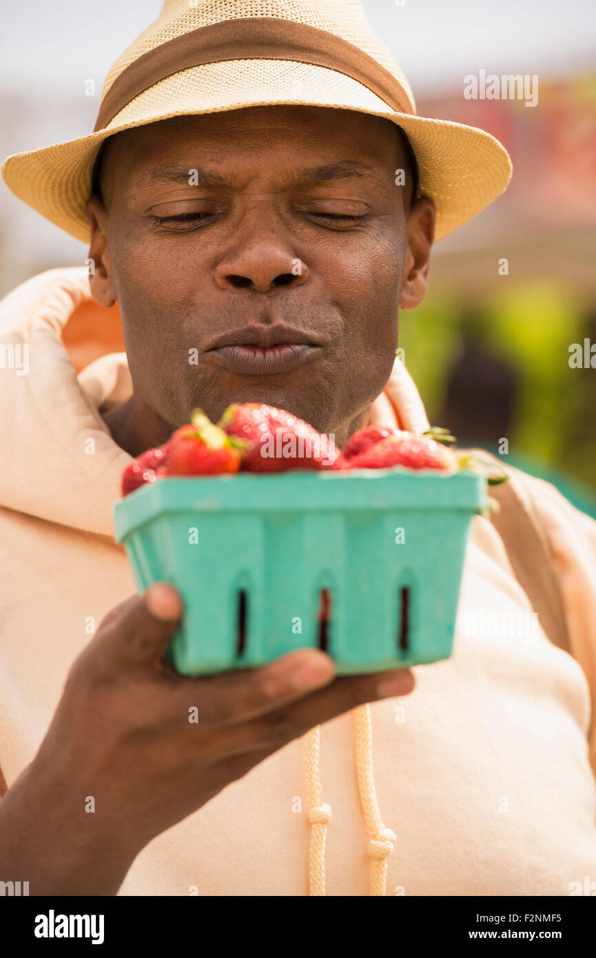 African American man examining basket of strawberries Stock Photo