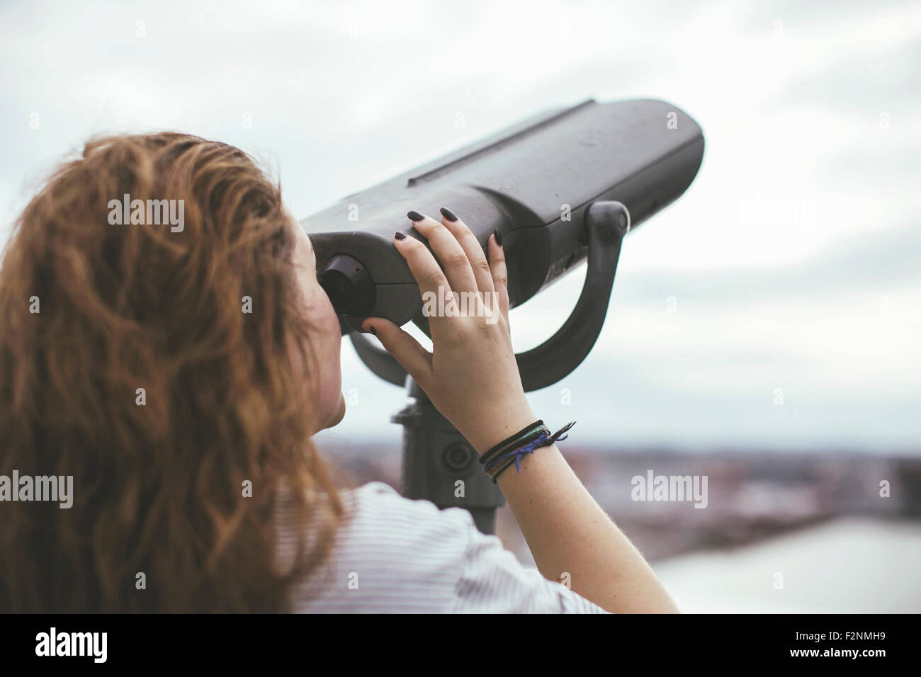 Caucasian woman on urban rooftop admiring cityscape with telescope Stock Photo