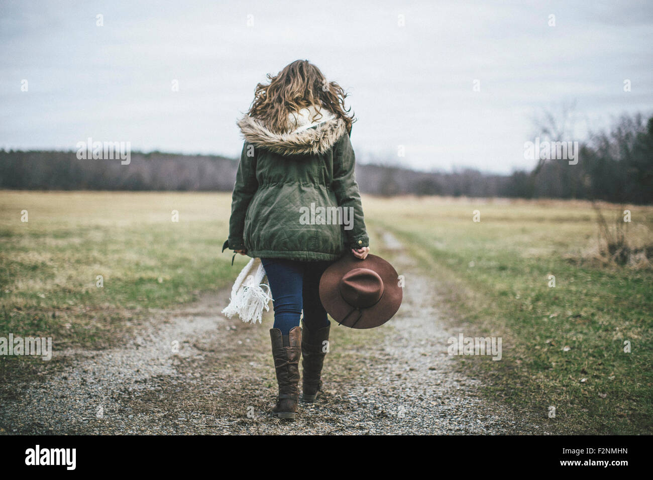 Caucasian woman walking on dirt path in rural field Stock Photo