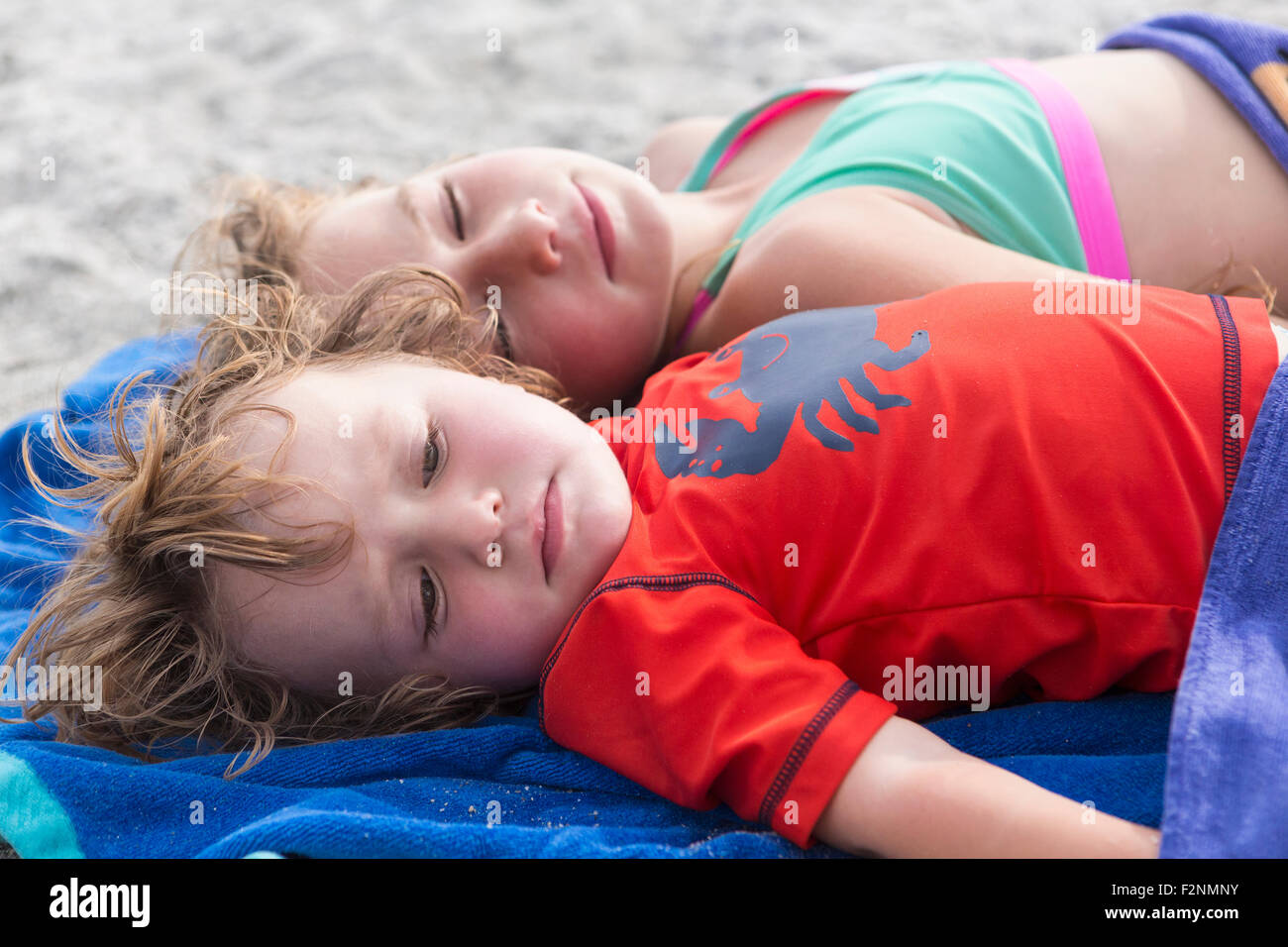 Caucasian brother and sister napping on beach Stock Photo