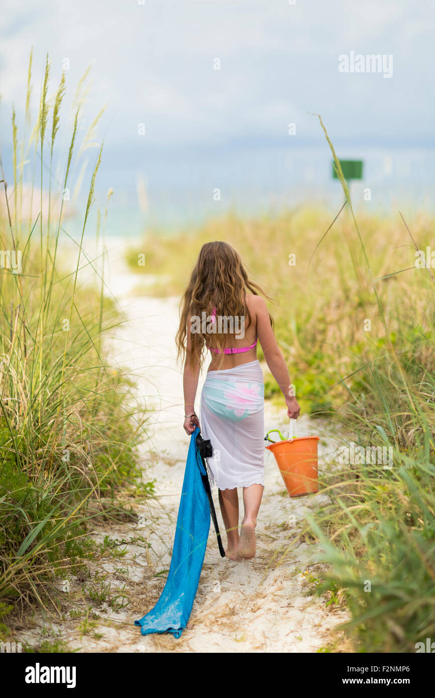 Caucasian girl carrying pail and towel on beach Stock Photo