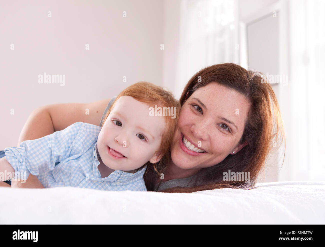 Smiling mother and son hugging on bed Stock Photo