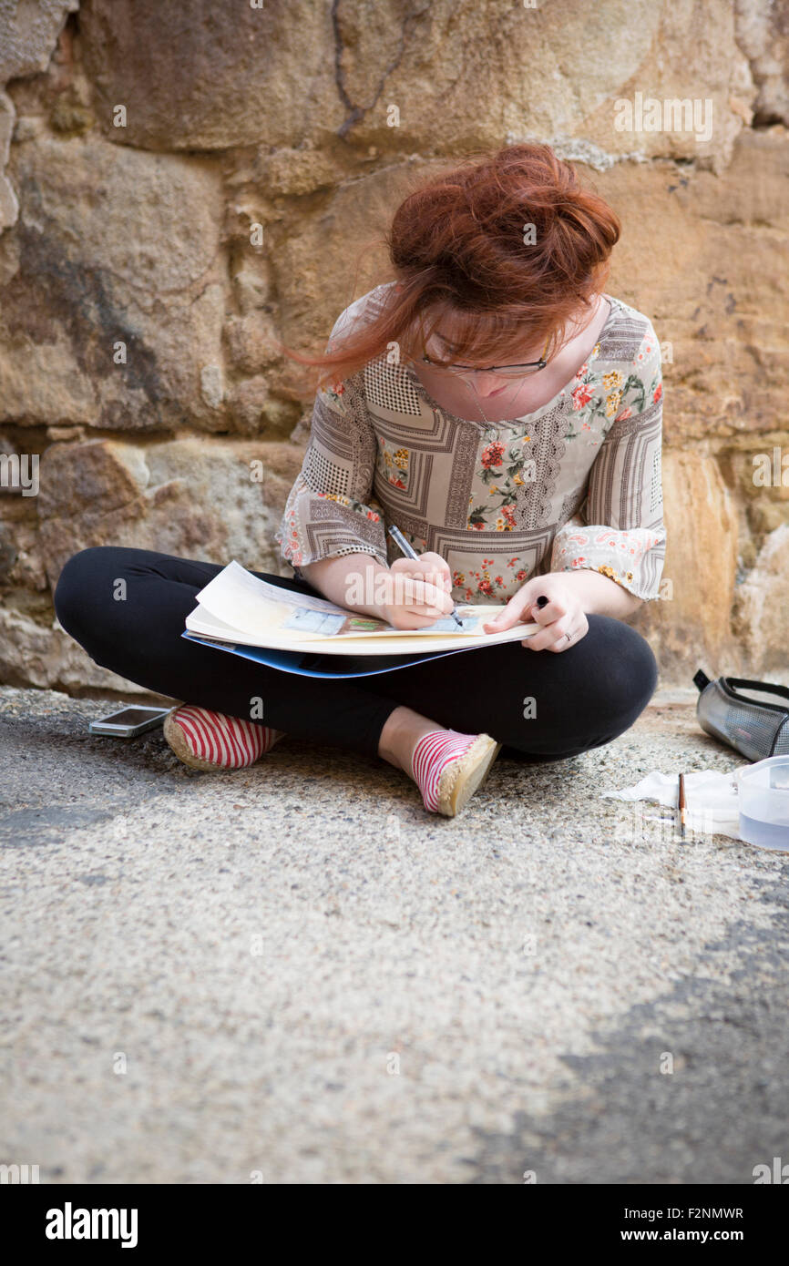 Caucasian girl drawing on concrete ground Stock Photo