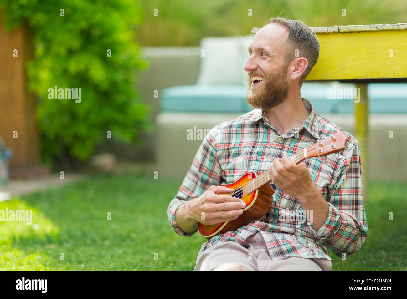 Caucasian man playing ukulele in backyard Stock Photo
