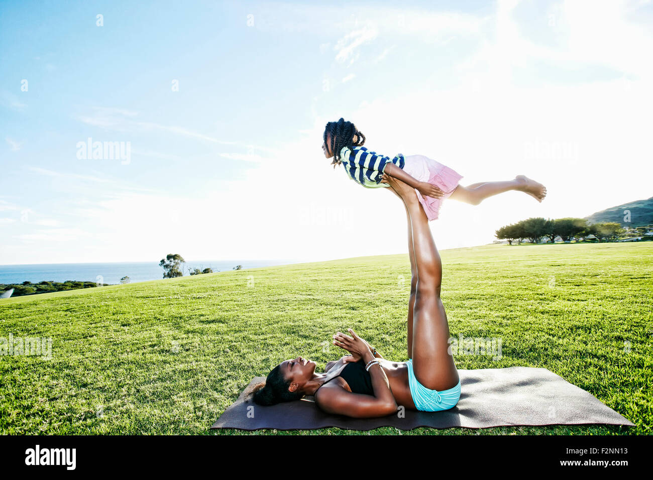 Mother holding daughter with legs in park Stock Photo