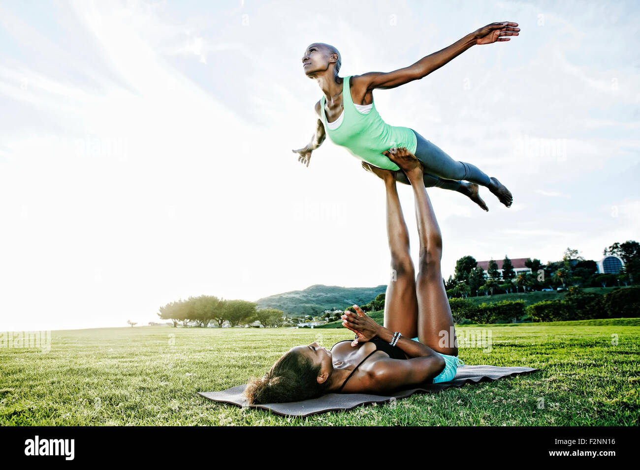 Woman and friend practicing acro yoga in park Stock Photo