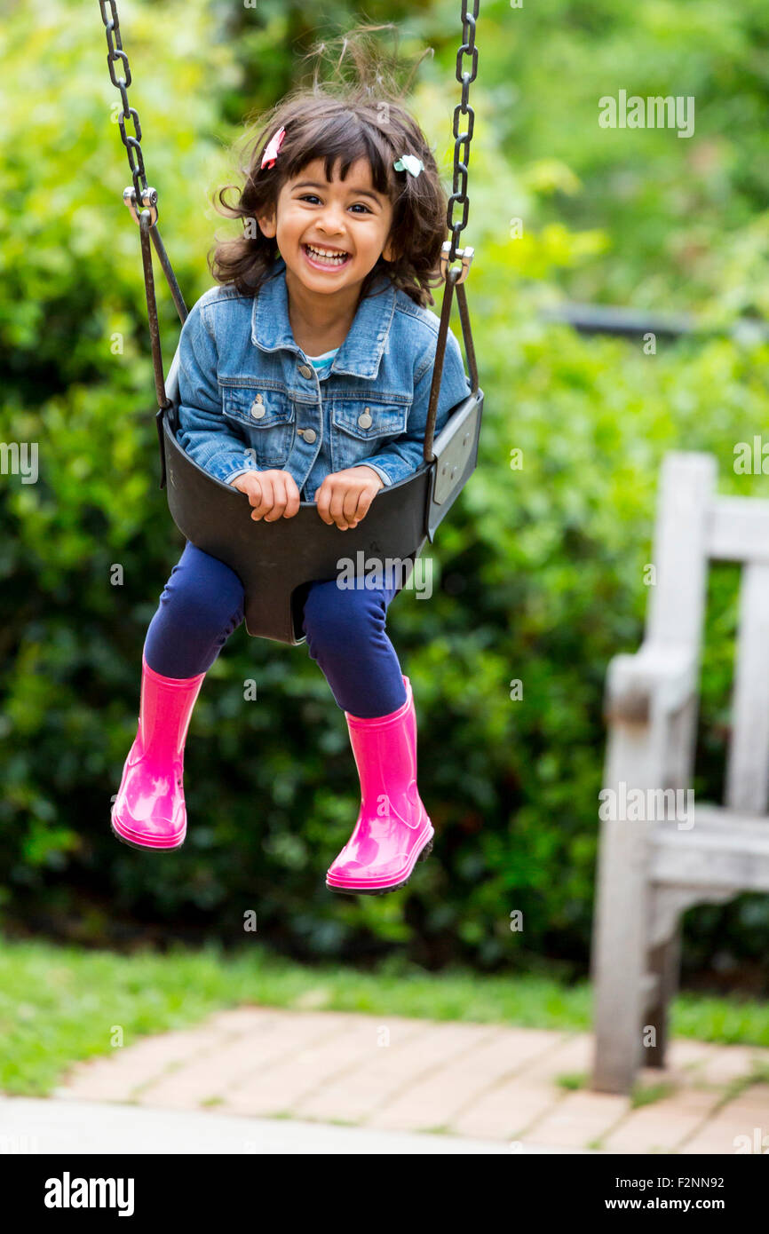Smiling girl playing in swing at playground Stock Photo - Alamy