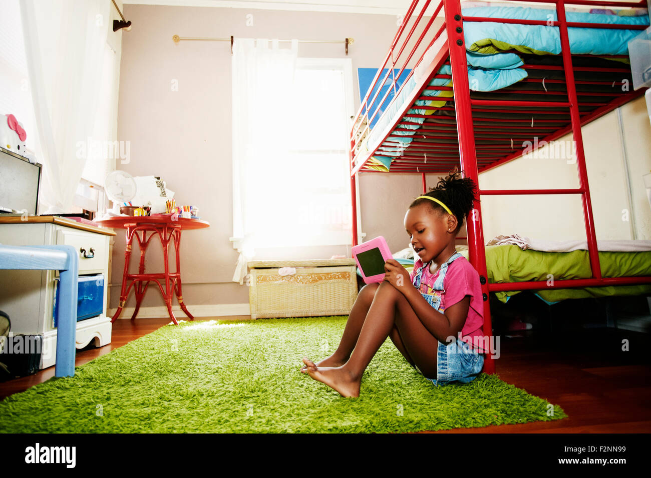 Black girl using digital tablet in bedroom Stock Photo