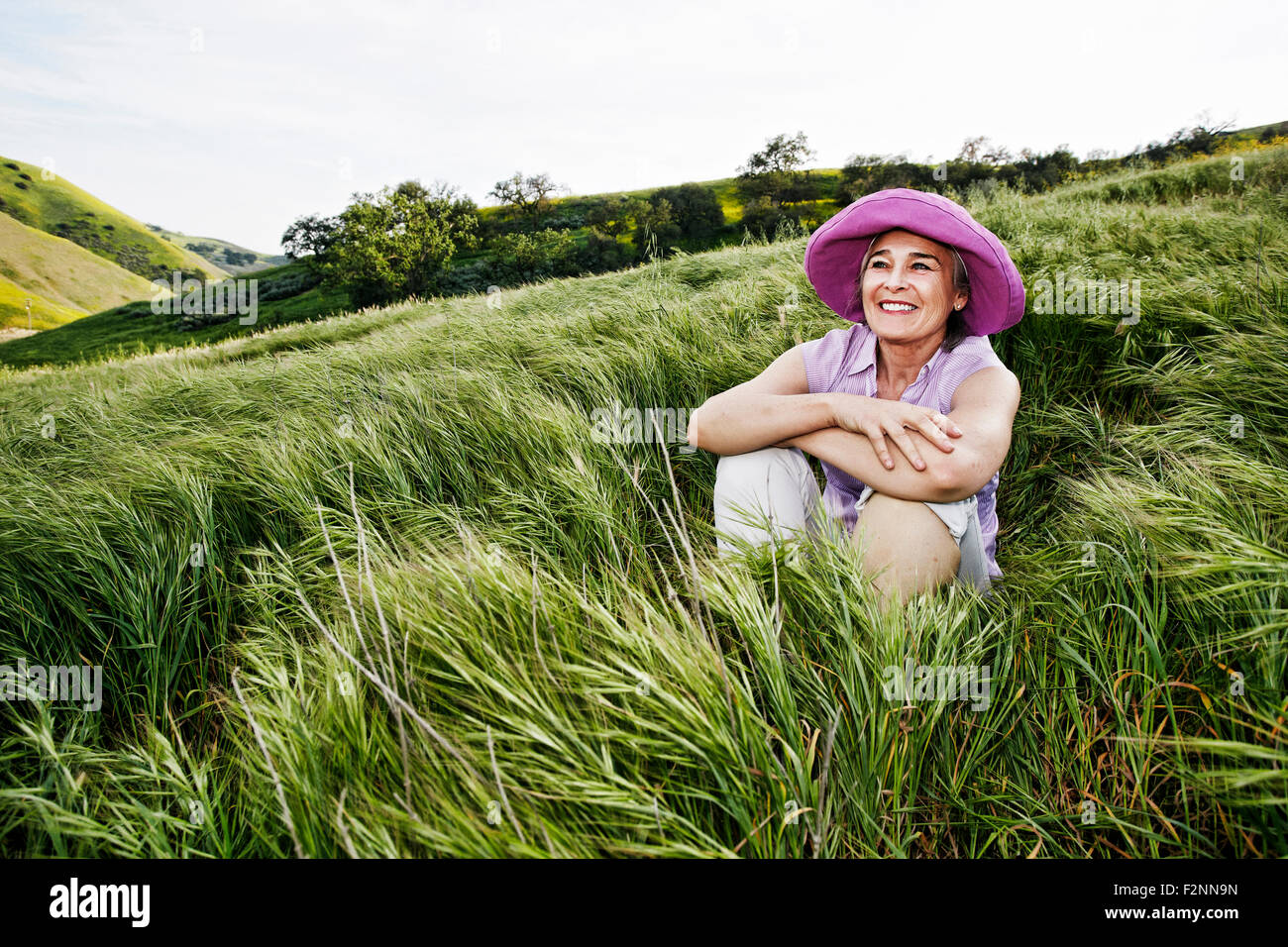 Caucasian woman sitting in tall grass Stock Photo