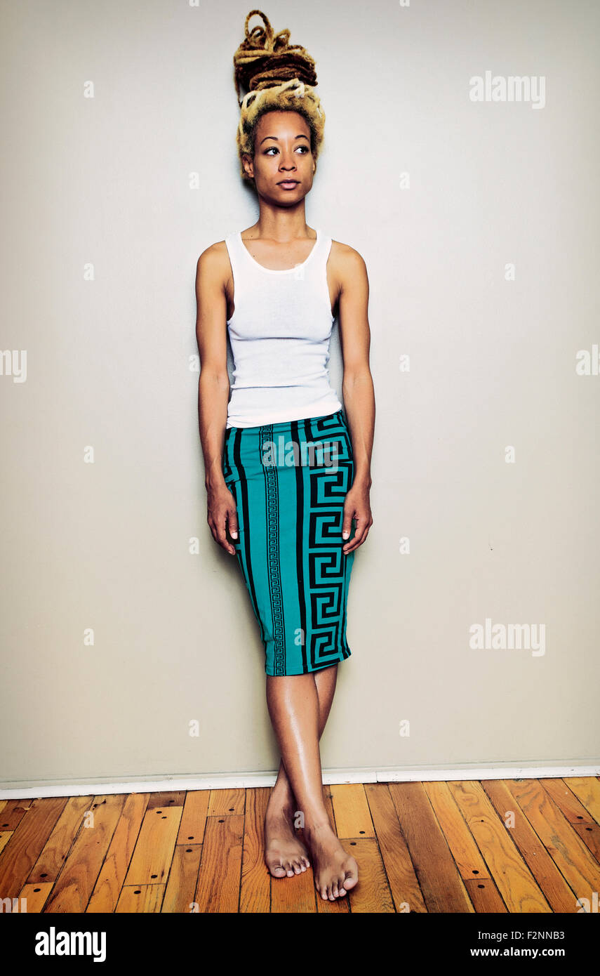 Black woman standing barefoot at wall Stock Photo