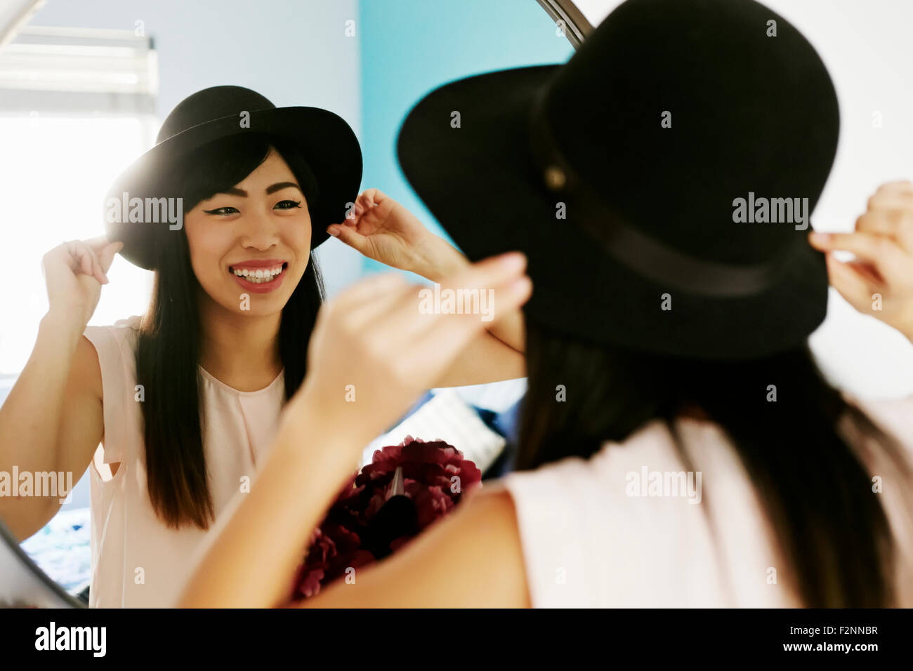 Japanese woman adjusting hat in mirror Stock Photo