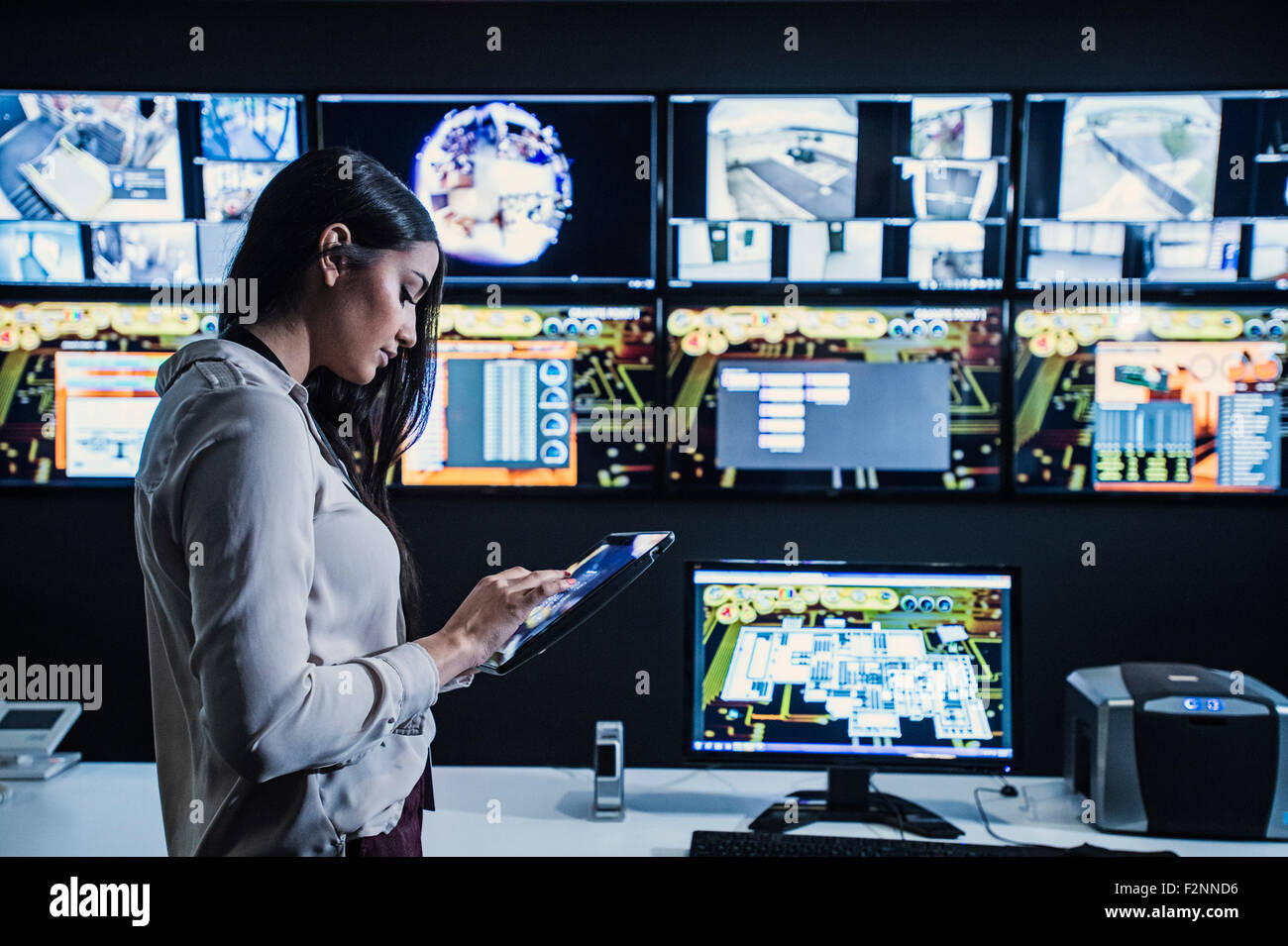 Hispanic security guard using digital tablet in control room Stock Photo