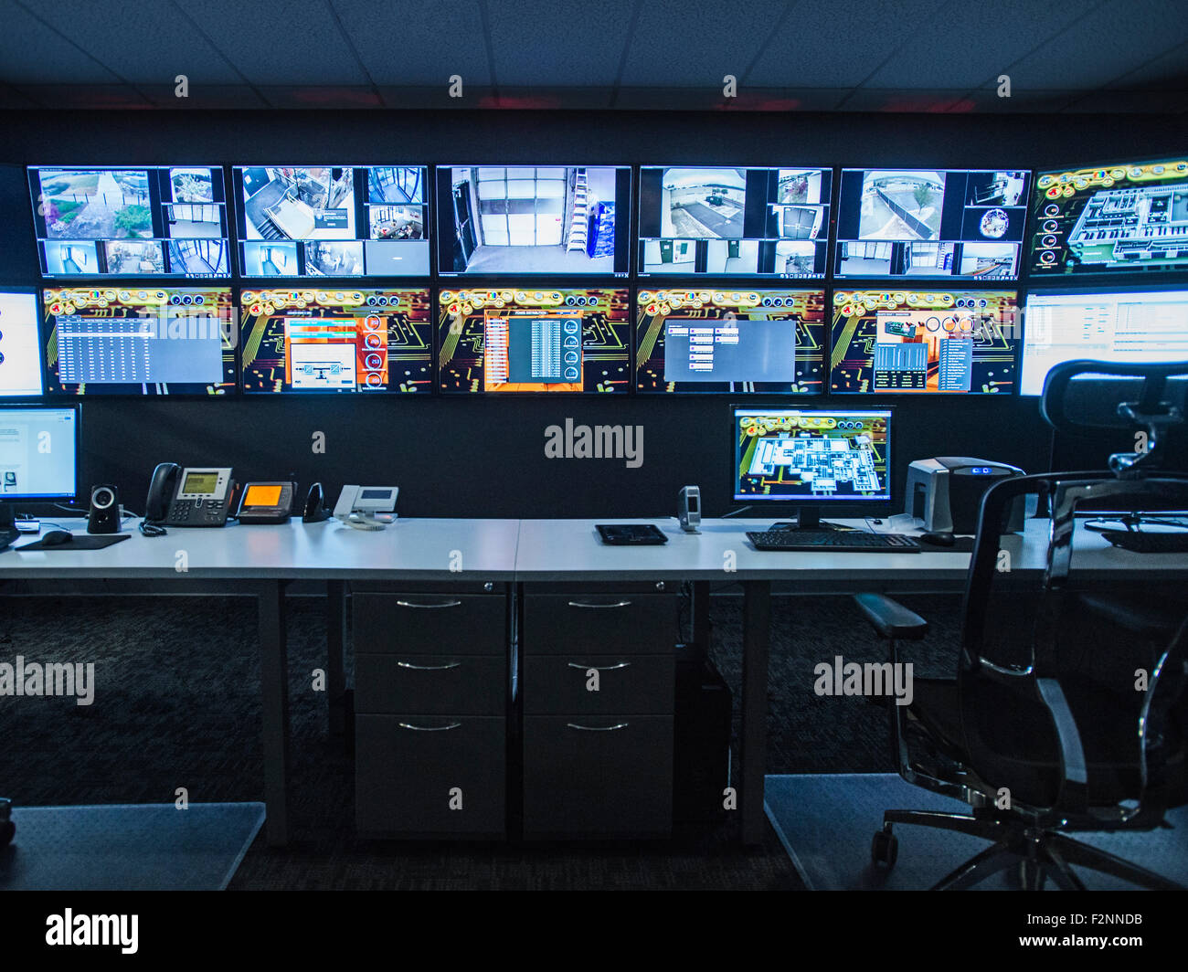 Monitors and empty desk in control room Stock Photo