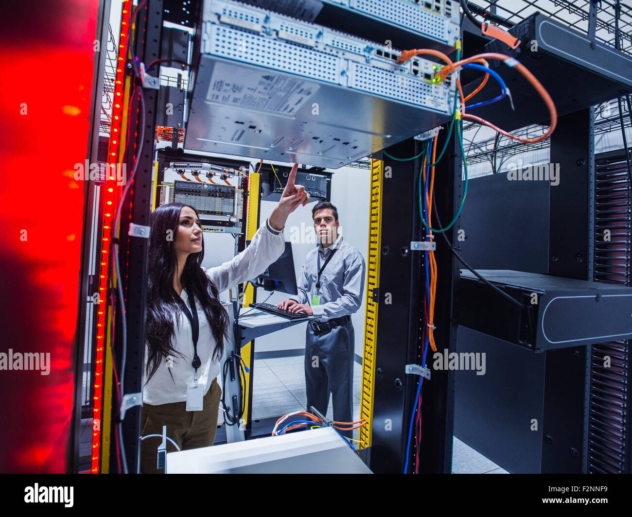 Technicians examining computer in server room Stock Photo