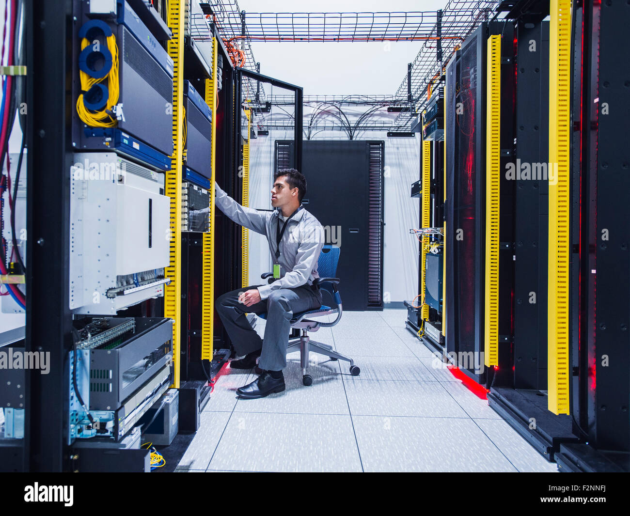 Hispanic technician examining computer in server room Stock Photo