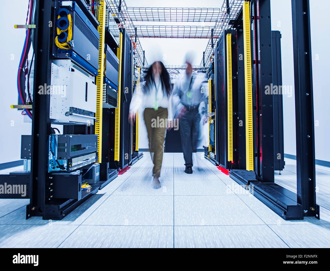 Blurred view of technicians walking in server room Stock Photo