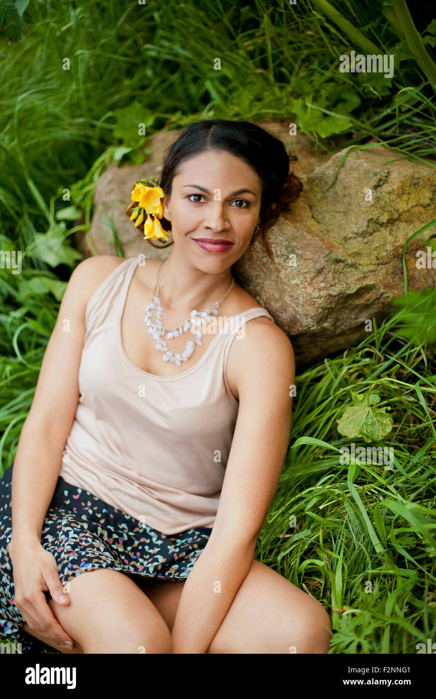 Mixed race woman laying on rock in tall grass Stock Photo