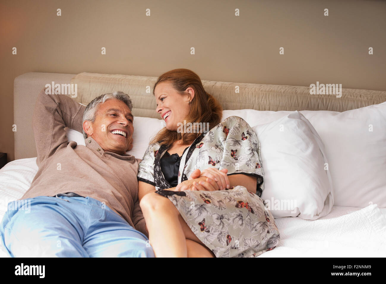 Laughing couple relaxing on bed Stock Photo