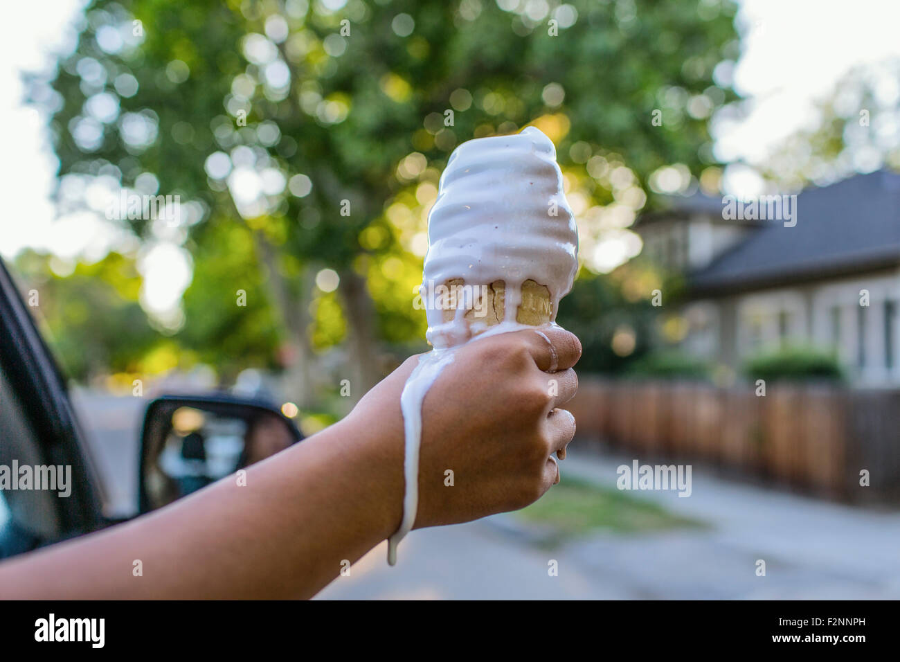 Close up of hand of Chinese girl holding melting ice cream cone Stock