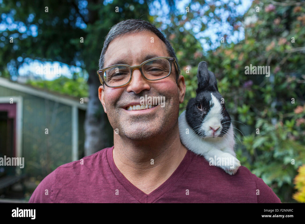 Mixed race man carrying rabbit on shoulder Stock Photo