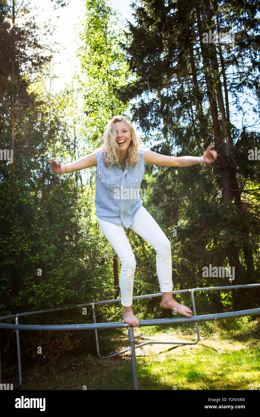 Woman jumping from metal structure in backyard Stock Photo