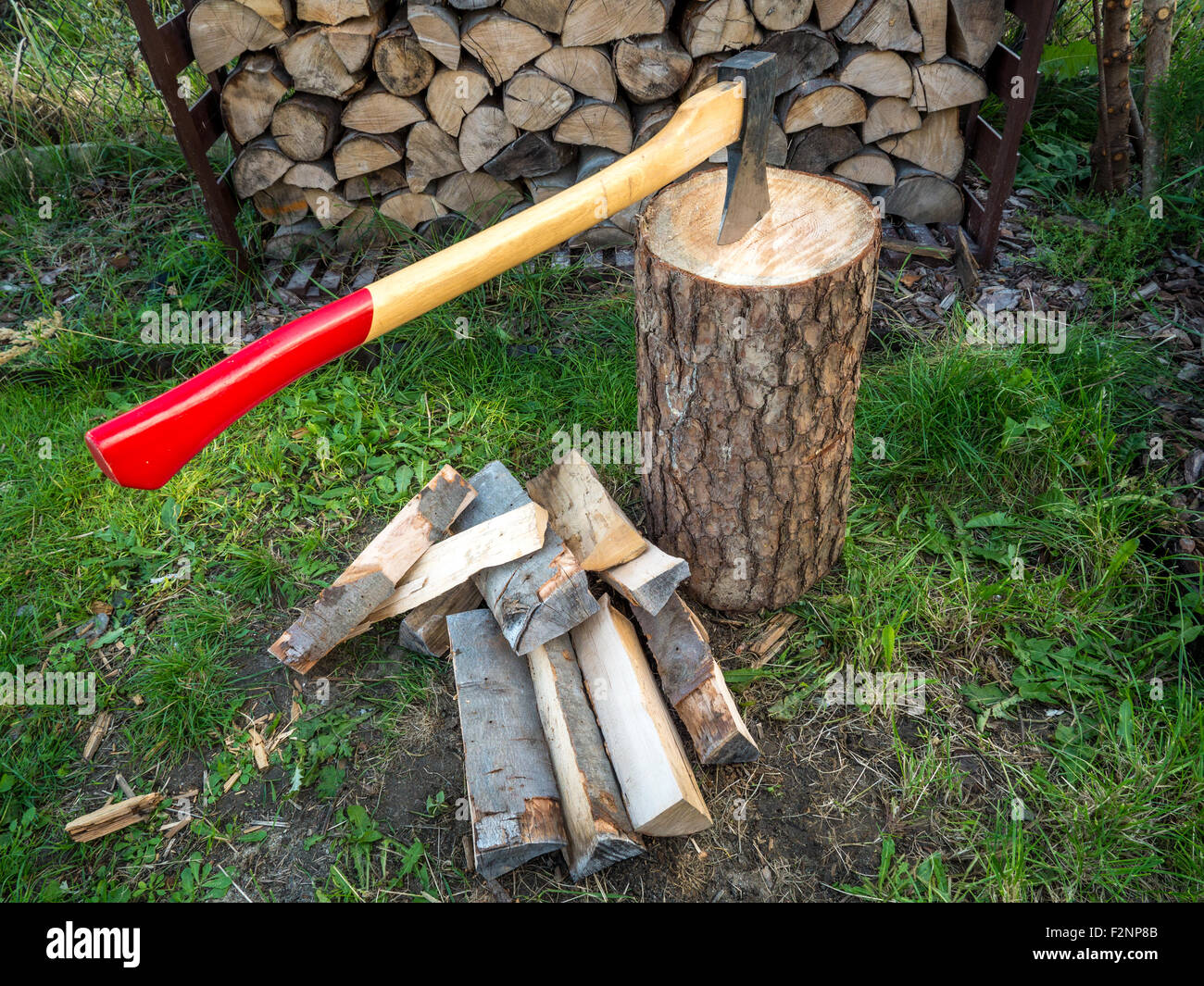 Axe on chopping block with chopped logs Stock Photo