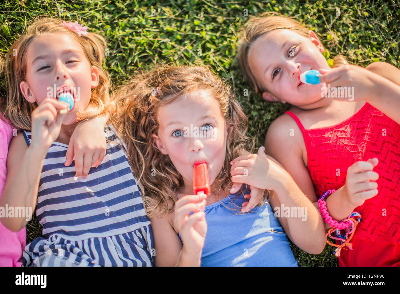 Girls eating flavored ice in grass Stock Photo