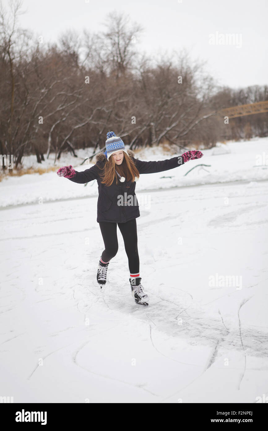 Caucasian teenage girl ice skating on frozen lake Stock Photo