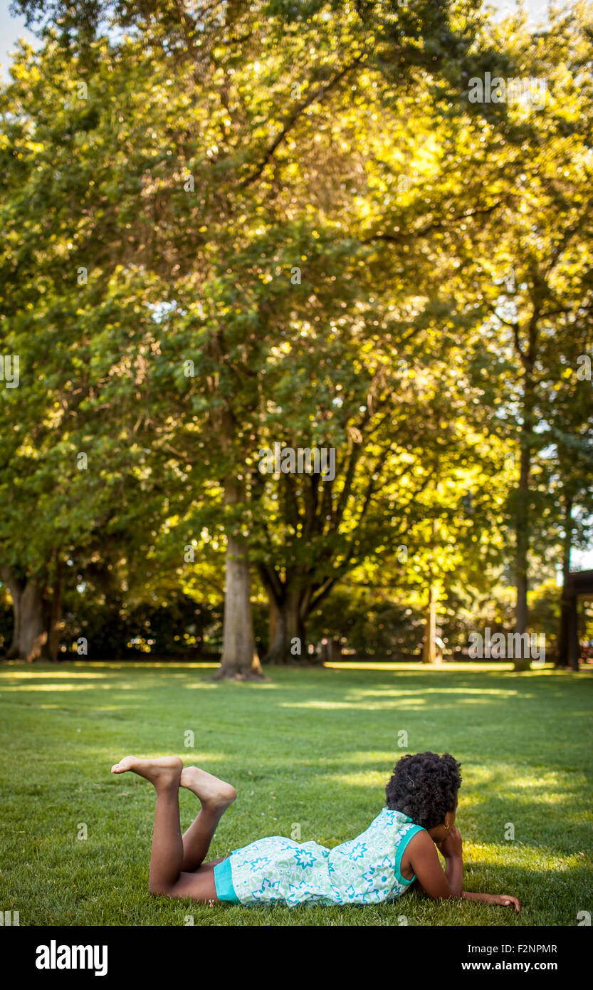 Girl laying in grass in park Stock Photo